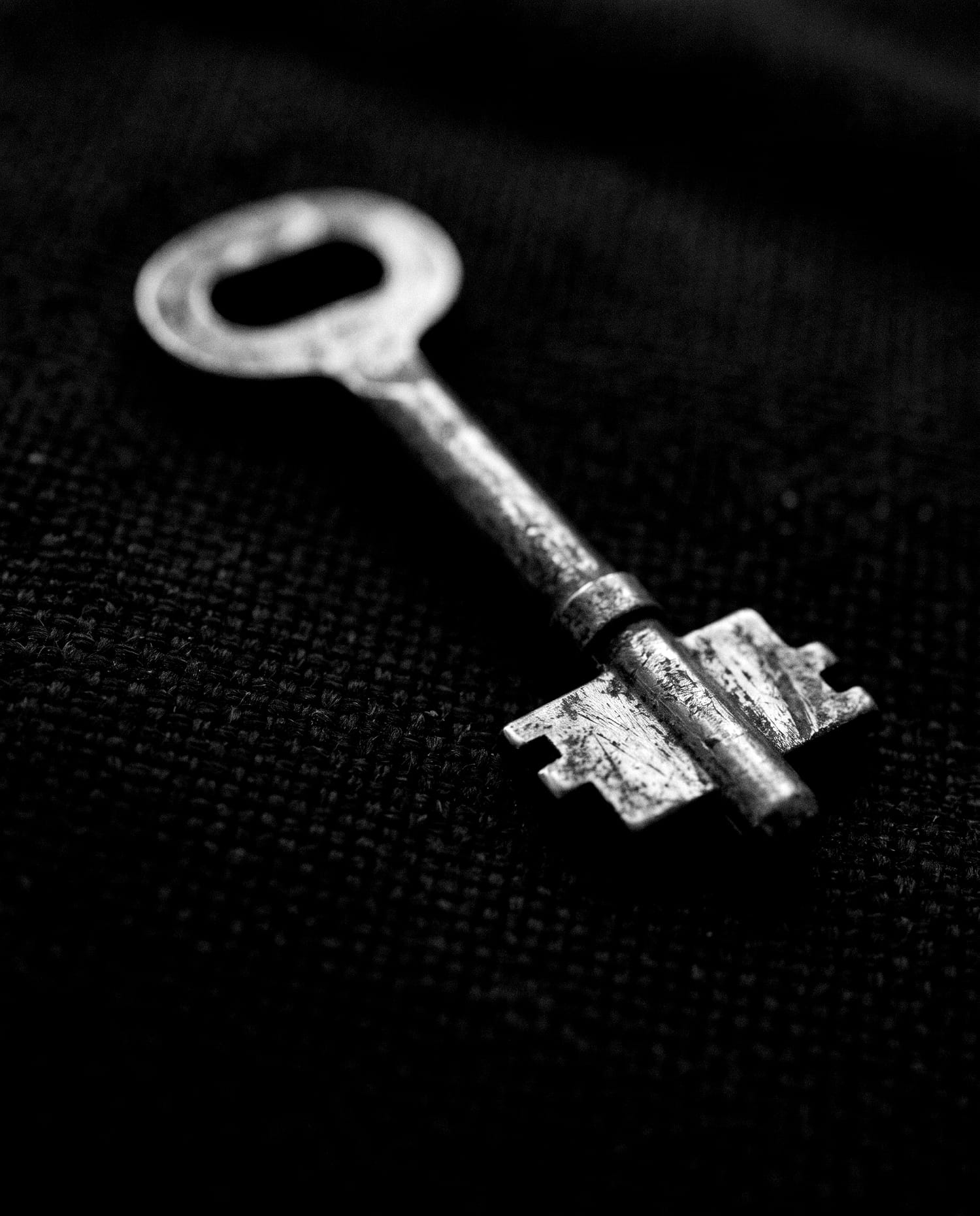 An old metal key on black cloth.